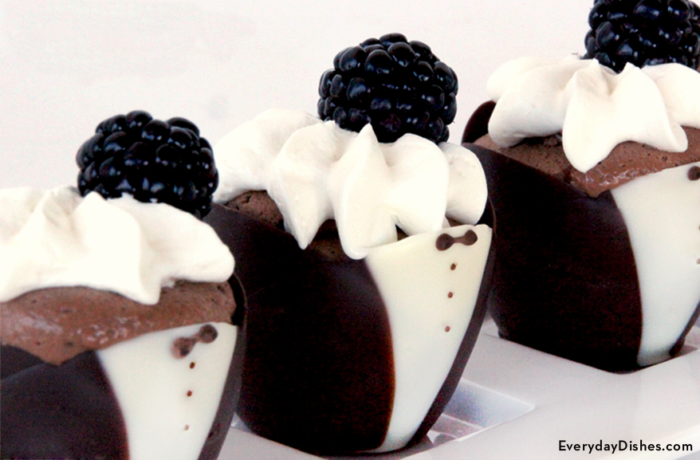 Chocolate mousse cups decorated to look like tuxedos and topped with whipped cream and blackberries.