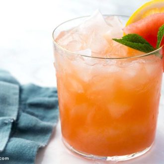 A refreshing glass of mango lemon watermelon cocktail, garnished with mint and watermelon.
