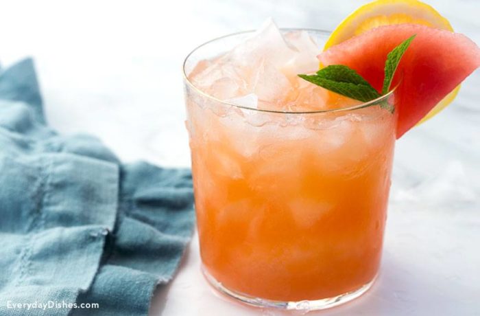 A refreshing glass of mango lemon watermelon cocktail, garnished with mint and watermelon.