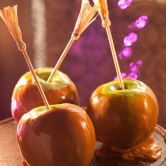 Three candy apples, dressed up Halloween treats with these DIY broom skewers.