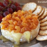 A delicious baked brie with apricot chutney topping, served with crackers and grapes.