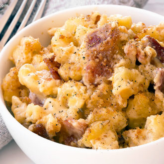 A bowl with a serving of homemade bacon mac and cheese casserole.