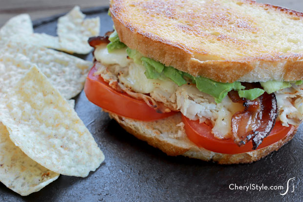 A quick and easy bacon turkey avocado melt, ready to enjoy with chips.