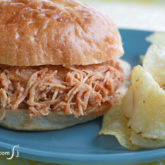 A delicious pulled BBQ chicken sandwich with a side of chips. A tasty lunch or dinner.