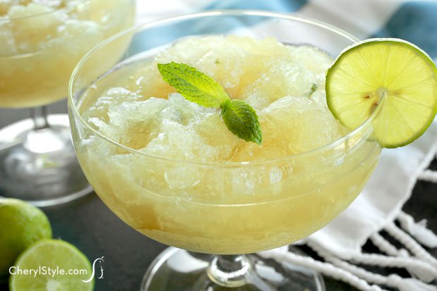 A glass of a delicious black rum limeade slush with mint, garnished with fresh mint and a slice of lime.