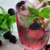 A delicious glass of blackberry rum spritzer cocktail that's garnished with mint and fresh blackberries