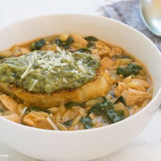 A bowl of delicious chicken orzo soup with spinach that's ready to eat.