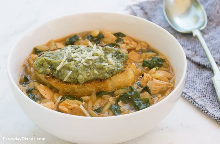 A bowl of delicious chicken orzo soup with spinach that's ready to eat.