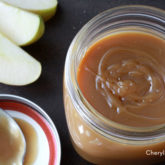 Fast and easy homemade butterscotch sauce topping in a jar, with some fresh fruit ready to be dipped into it.