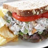 A tarragon chicken salad with grapes and zesty lemon, on a plate with some chips.