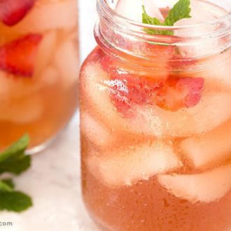 A tasty muddled strawberry mint tea in a mason jar with ice.