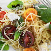 A plate of cherry tomato pasta salad with fresh mozzarella, a delicious side dish.