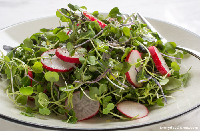 A plate with a micro green salad with lime dressing.