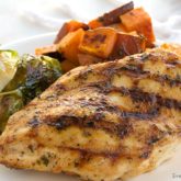 Moist grilled chicken, on a plate with a veggie side, a healthy and tasty dinner.