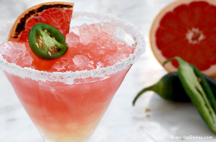 A delicious spicy grapefruit margarita, garnished with a grapefruit slice and jalapeño