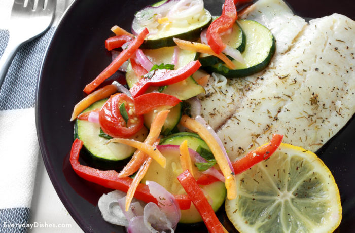 A plate of baked tilapia with veggies, ready to enjoy for dinner.