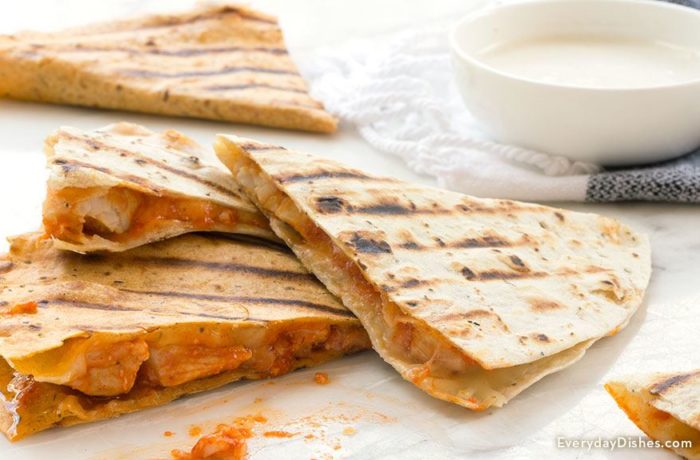 A fresh batch of buffalo chicken quesadillas with a bowl of dipping sauce.