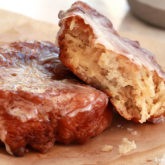 Two homemade apple fritters on a plate.