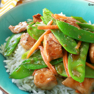 Sauteed chicken and snow peas, served on a plate over rice.