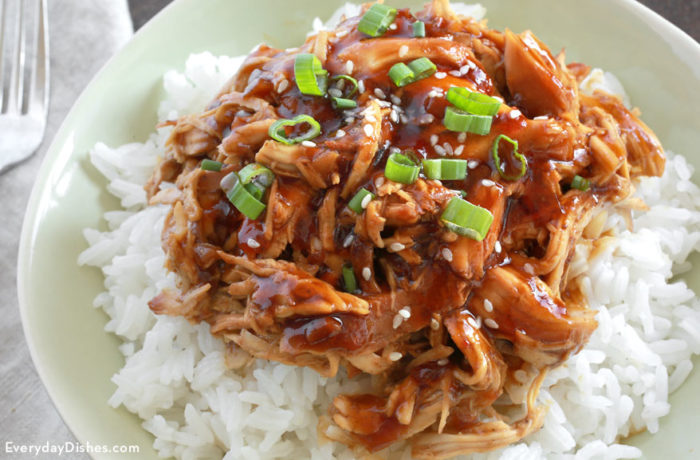 Slow cooker honey garlic chicken, served in a bowl over rice.