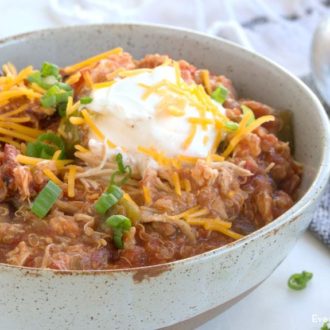 A bowl of slow cooker quinoa chicken chili, garnished with sour cream and cheese