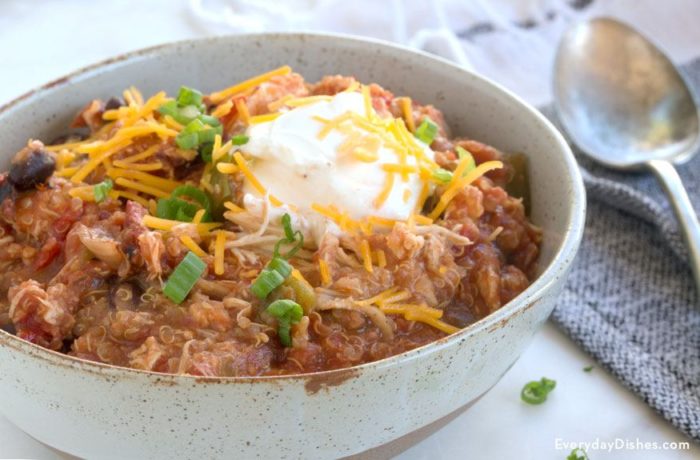 A bowl of slow cooker quinoa chicken chili, garnished with sour cream and cheese