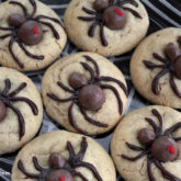 A fresh batch of Halloween spider cookies on a plate with webs. A Spooktacular treat!