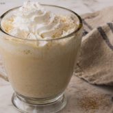 A delicious mug of pumpkin spice white hot chocolate topped with whipped cream and cinnamon.