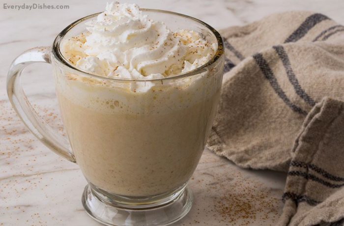 A delicious mug of pumpkin spice white hot chocolate topped with whipped cream and cinnamon.