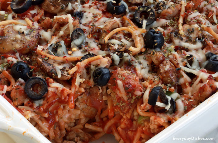 A homemade pizza spaghetti bake with a serving missing.