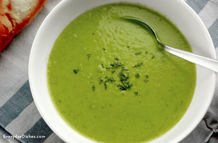 A bowl of sweet pea soup with a spoon in it, ready to take that first bite.