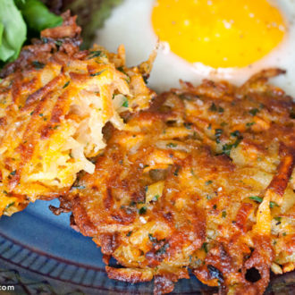 Two homemade veggie potato patties on a plate with an egg, ready to serve.