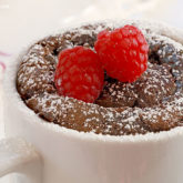 A delicious, gooey chocolate mug cake, topped with raspberries.