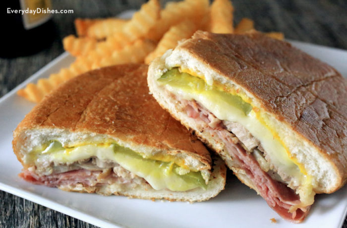 A delicious traditional Cuban sandwich with thin, crispy bread, savory sliced pork, melty cheese, and tangy pickles.