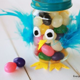 A DIY Easter treat jar that was made using felt, pom poms, and feathers.