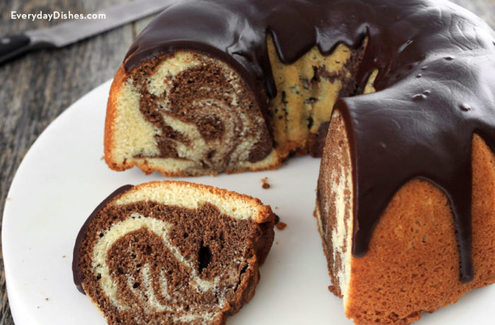 A classic marble cake with some pieces sliced off and served for dessert.