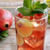 A refreshing glass of pomegranate mojito, garnished with mint and lime