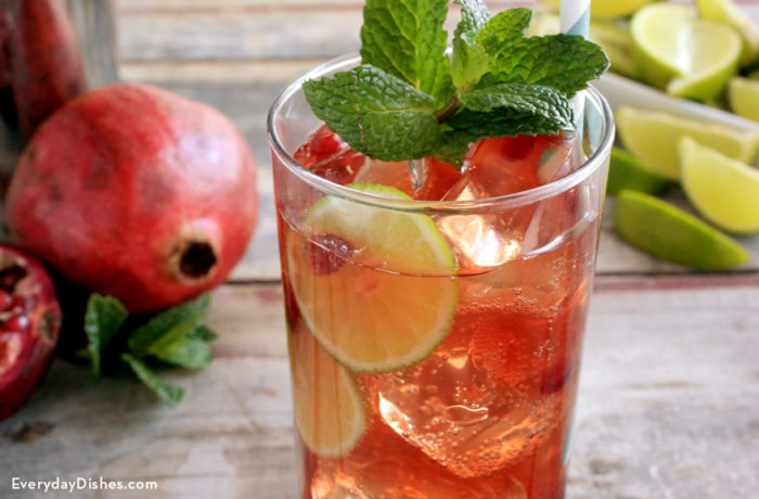 A refreshing glass of pomegranate mojito, garnished with mint and lime