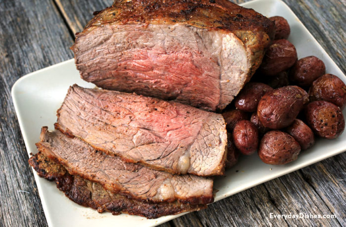 A perfect roast beef, sliced on a plate with potatoes, ready for dinner.