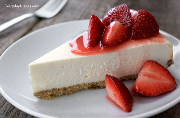 A slice of skinnier cheesecake, topped with strawberries — a healthier dessert option.