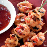 Some spicy Thai grilled shrimp on a plate with dipping sauce.