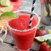 A glass of a strawberry ginger margarita recipe that's garnished with a lime wedge.