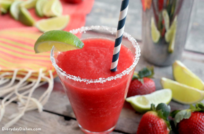 A glass of a strawberry ginger margarita recipe that's garnished with a lime wedge.