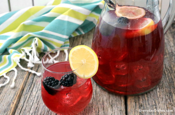 A glass and a pitcher of refreshing and homemade blackberry lemonade.
