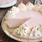 A freshly made no-bake lemonade pie with a slice cut out.