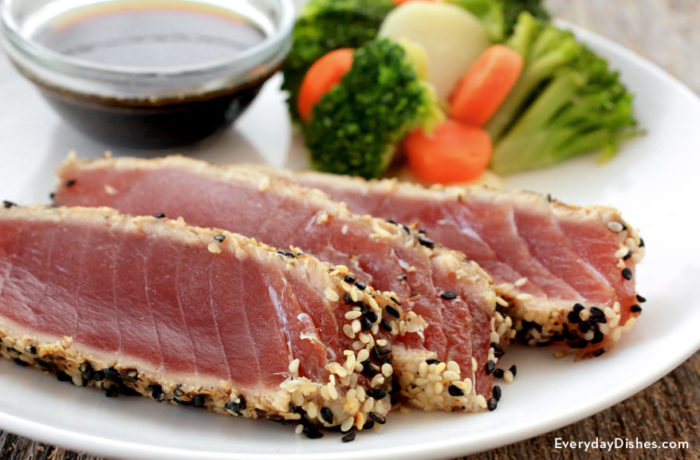 A plate of some sesame seared tuna steak with veggies on the side.
