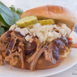 A slow cooker pulled pork sandwich on a plate with a side salad — a great dinner.