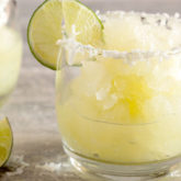 A glass full of a delightful coconut lime margarita garnished with lime and coconut.