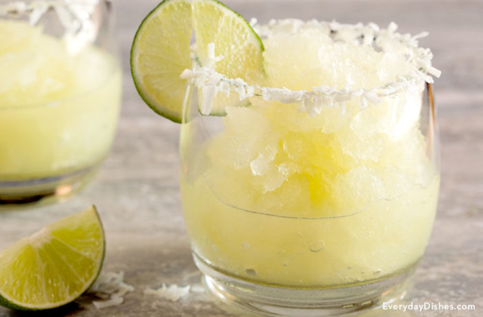 A glass full of a delightful coconut lime margarita garnished with lime and coconut.