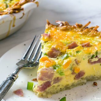 A slice of hash brown quiche with ham, on a plate and ready to eat.